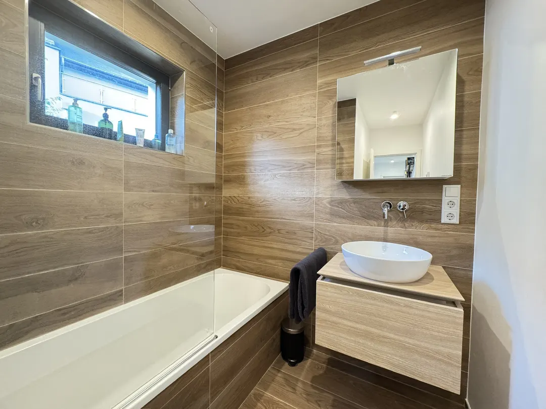 Salle de bains avec baignoire, vasque sur meuble et fenêtre