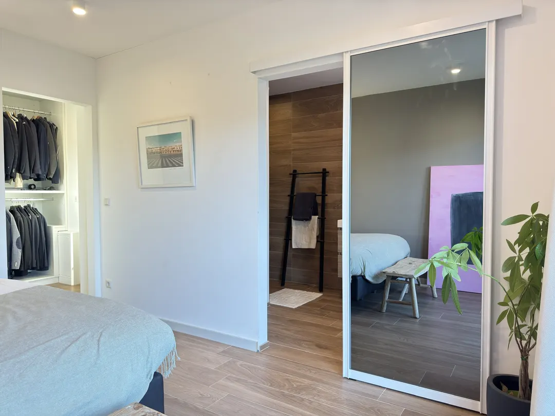 Chambre avec vue sur le dressing et porte coulissante à miroir vers la salle de bains