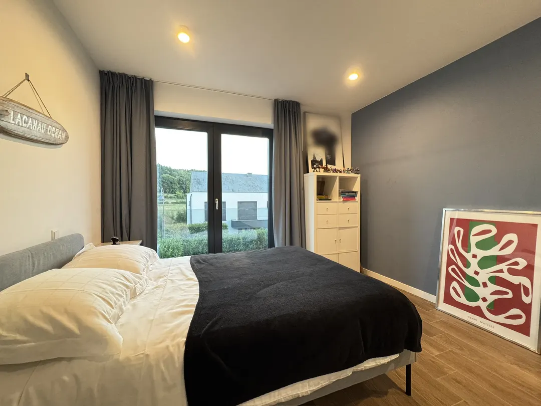 Chambre avec lit, rideaux et porte-fenêtre donnant sur les champs