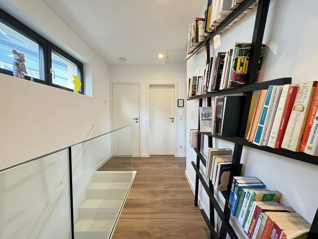 Palier avec garde-corps en verre, étagères à livres et fenêtre haute