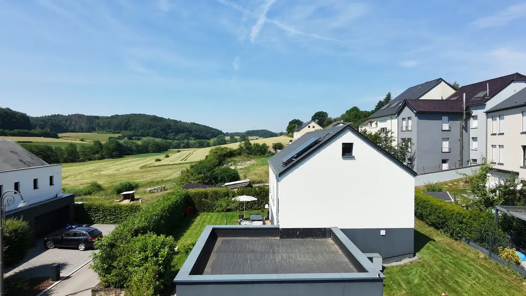 Vue aérienne du jardin : haie, parasol, terrasse et prairie derrière