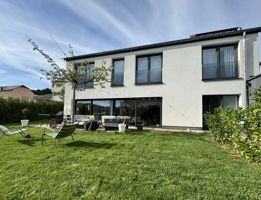 Façade côté jardin en plein jour, terrasse et pelouse, chaises de jardin