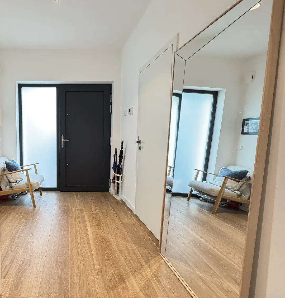Hall d'entrée avec parquet en chêne, porte d'entrée vitrée et grand miroir